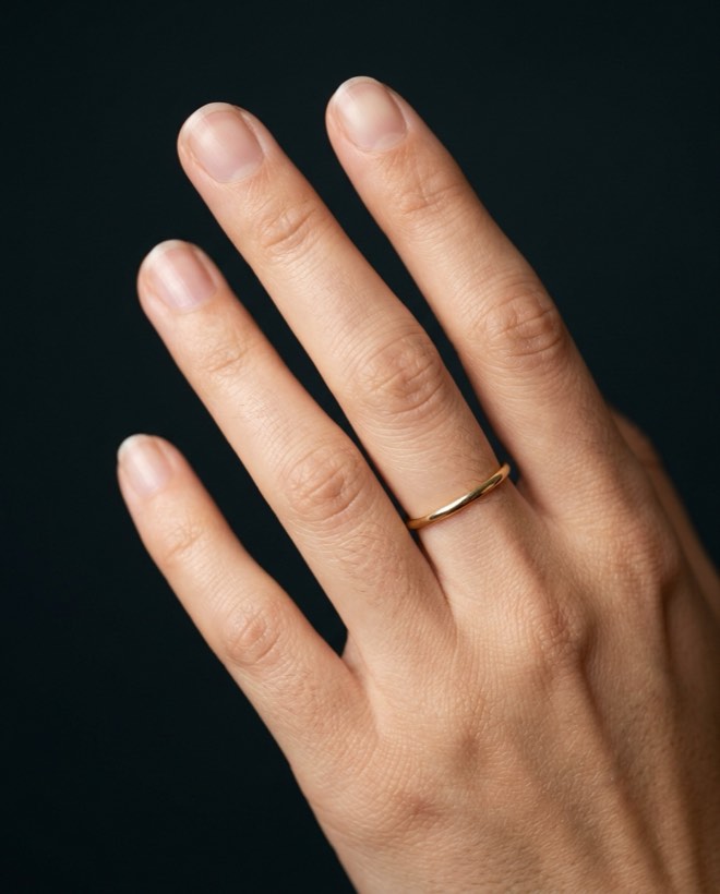 A hand with short, bare natural nails and a thin gold ring